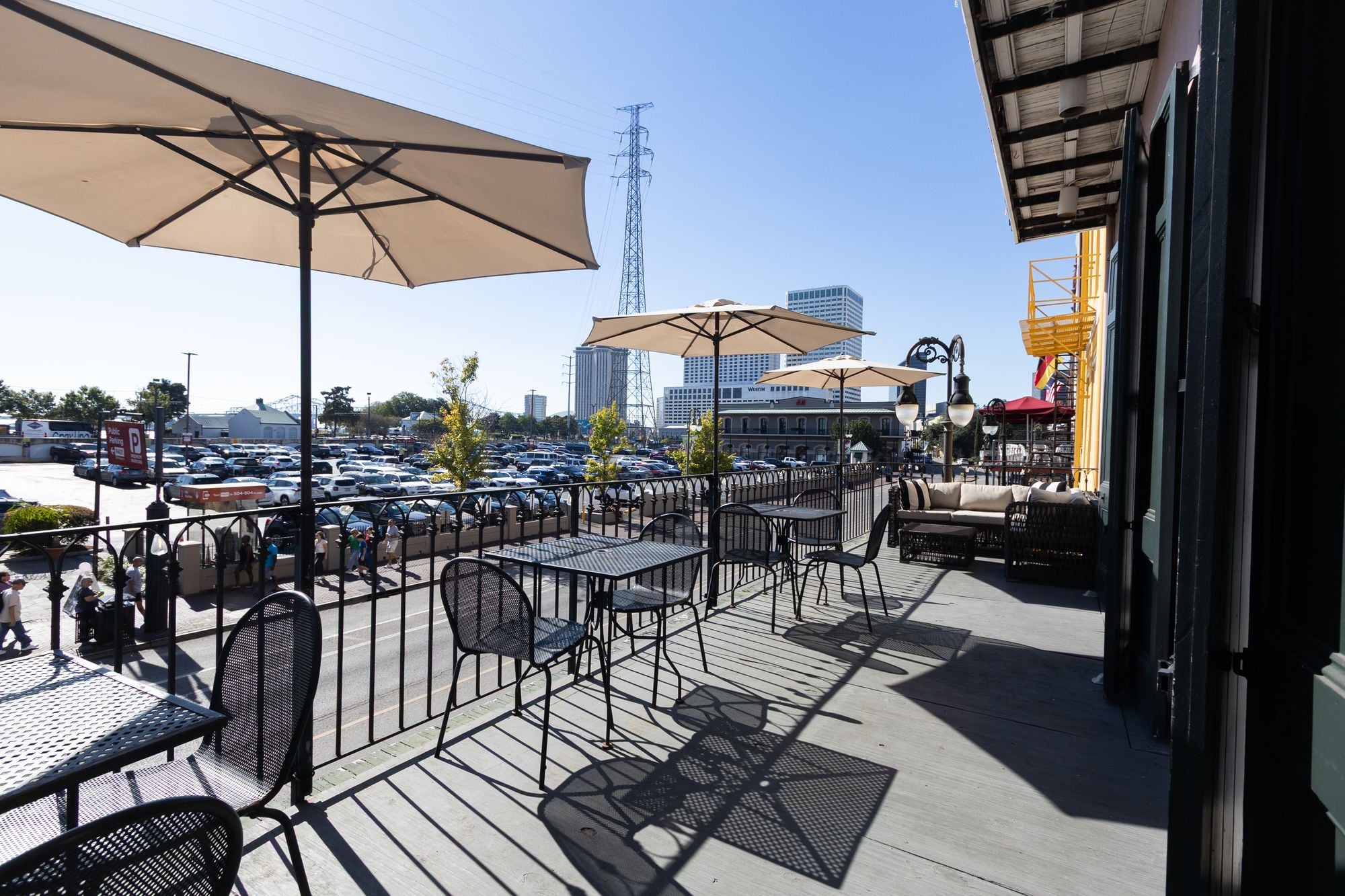 Umbrella-covered balcony tables overlooking Decatur Street and the New Orleans skyline