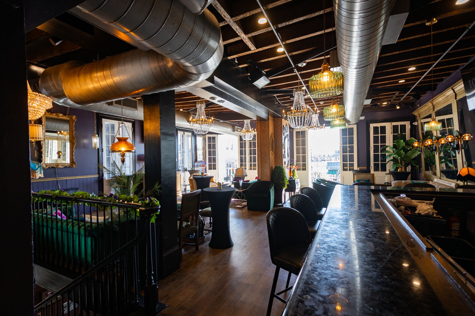 Granite bar and lounge seating beneath exposed ductwork and brass lanterns