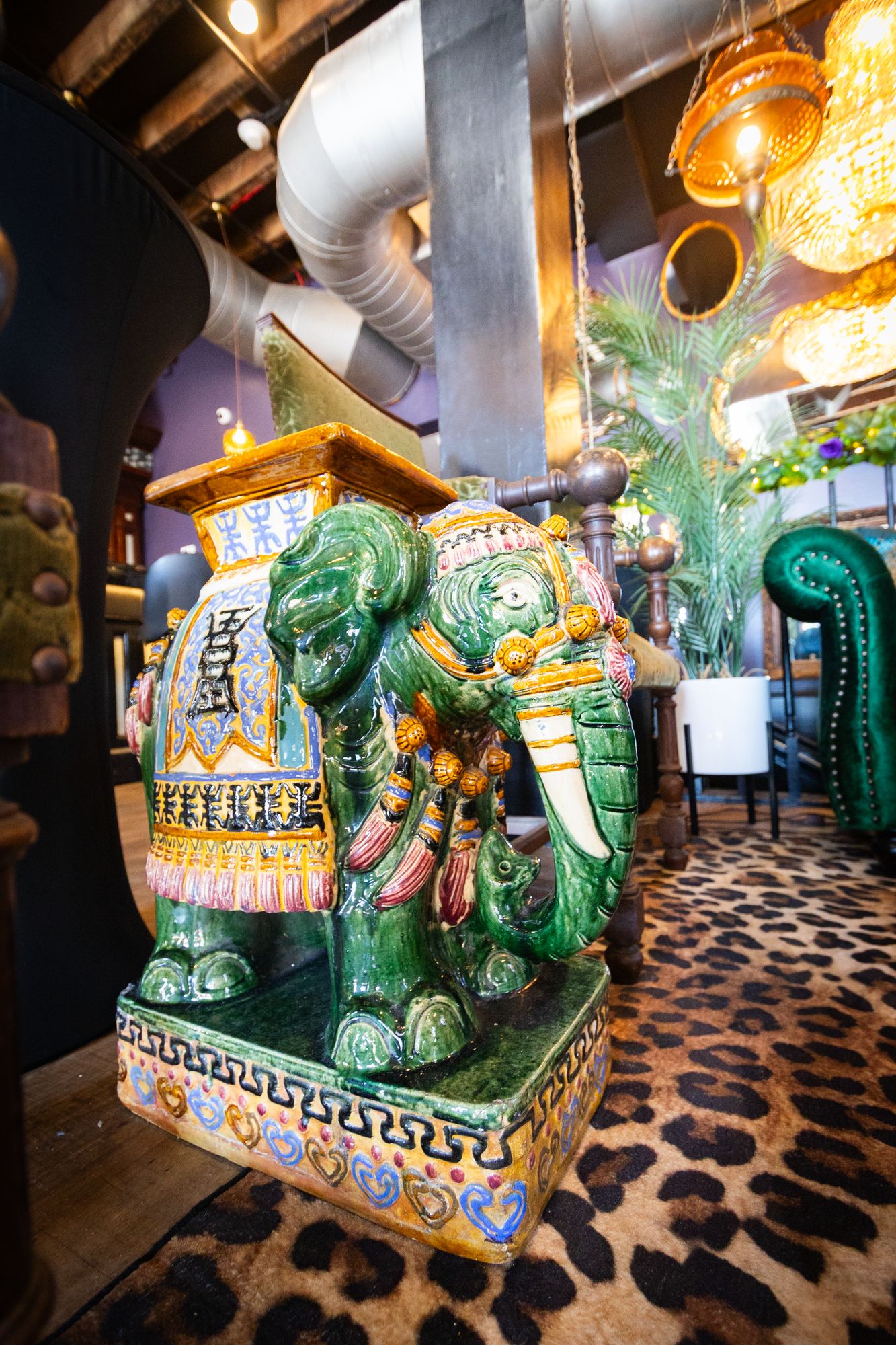 Hand-painted green ceramic elephant on a leopard-print carpet