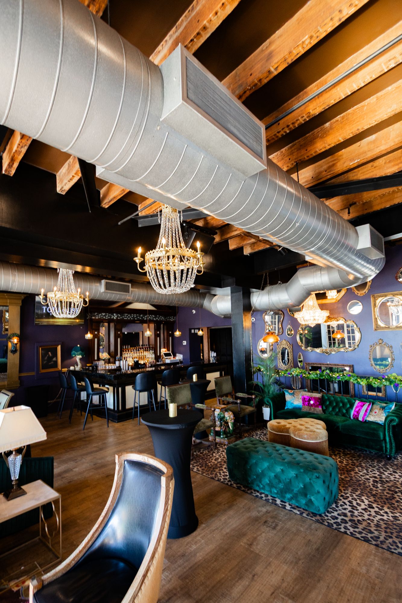 Lounge beneath silver ductwork, exposed beams and chandeliers