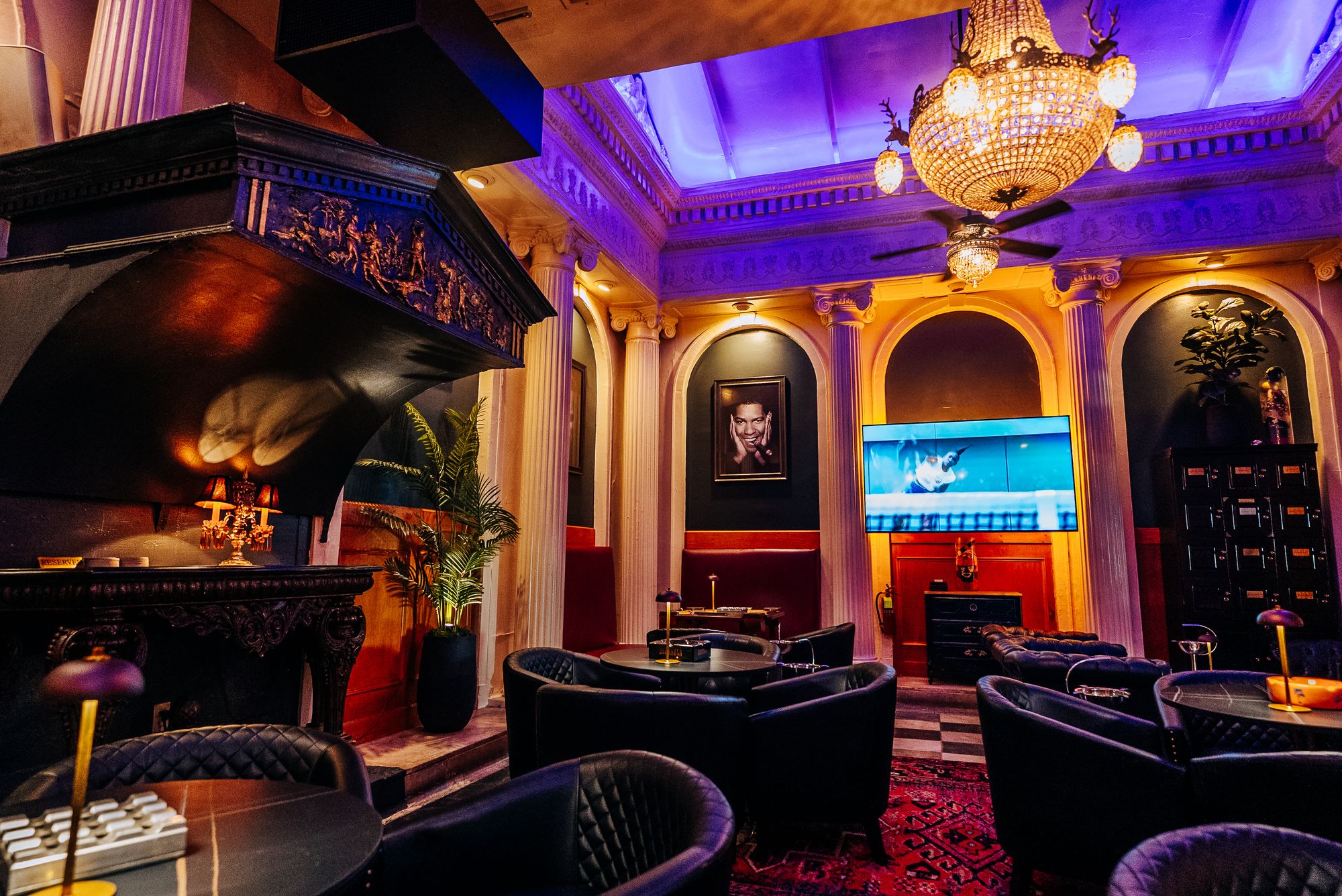 Lounge with a carved fireplace, crystal chandelier and big screen