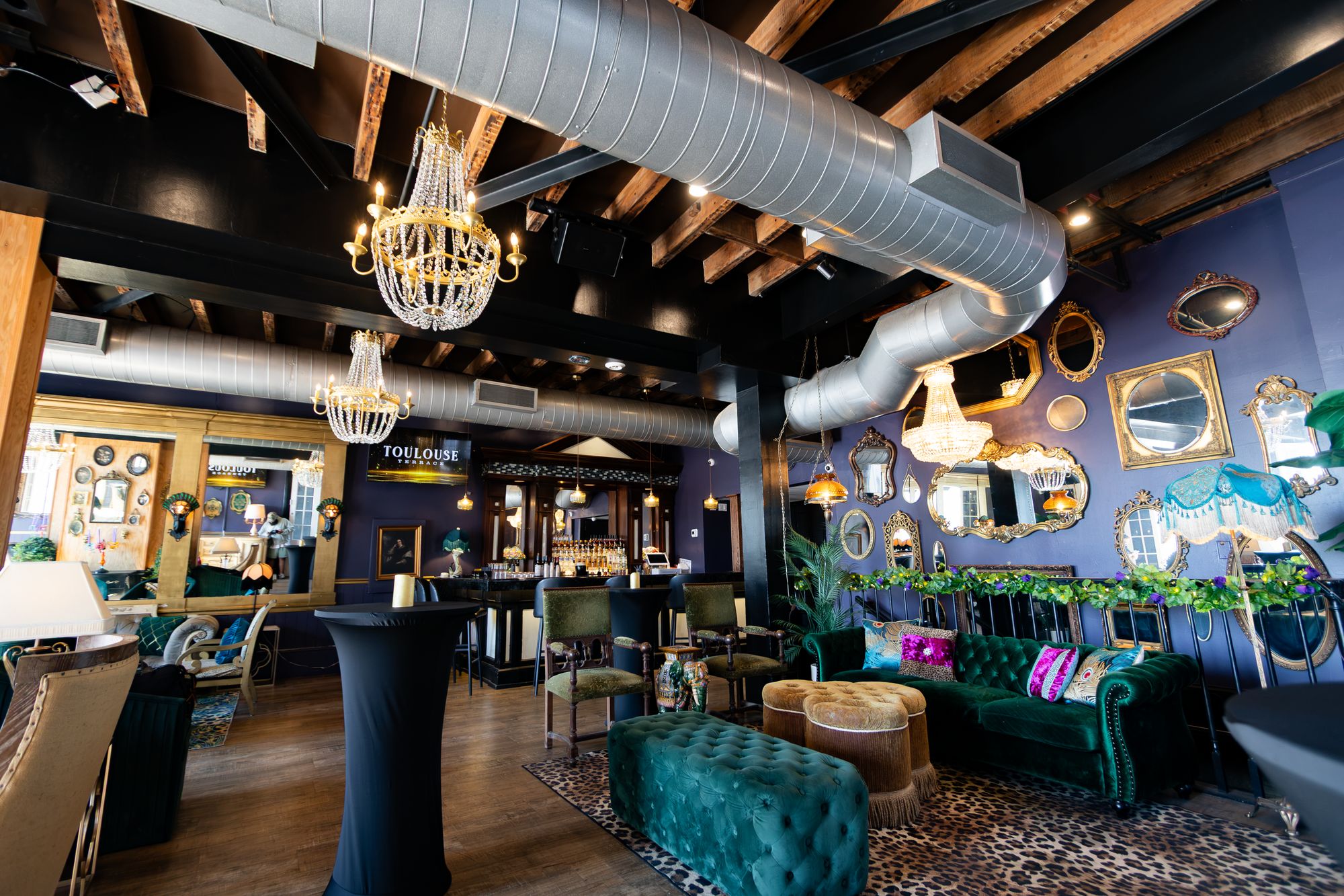 Full view of the event room with ductwork ceiling, chandeliers and lounge groupings