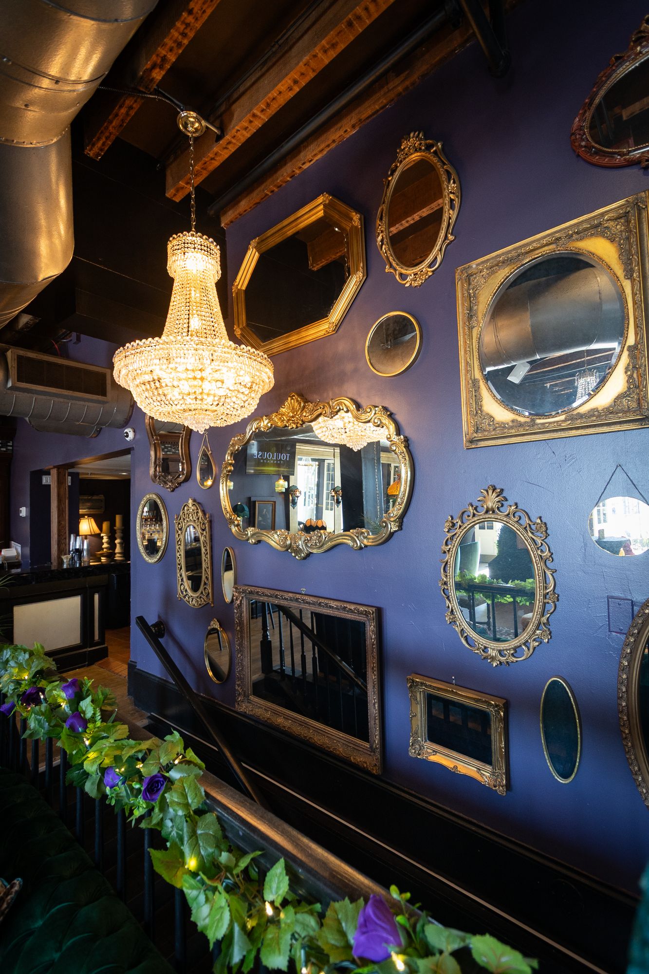 Gilded mirrors above a greenery-draped railing in the lounge