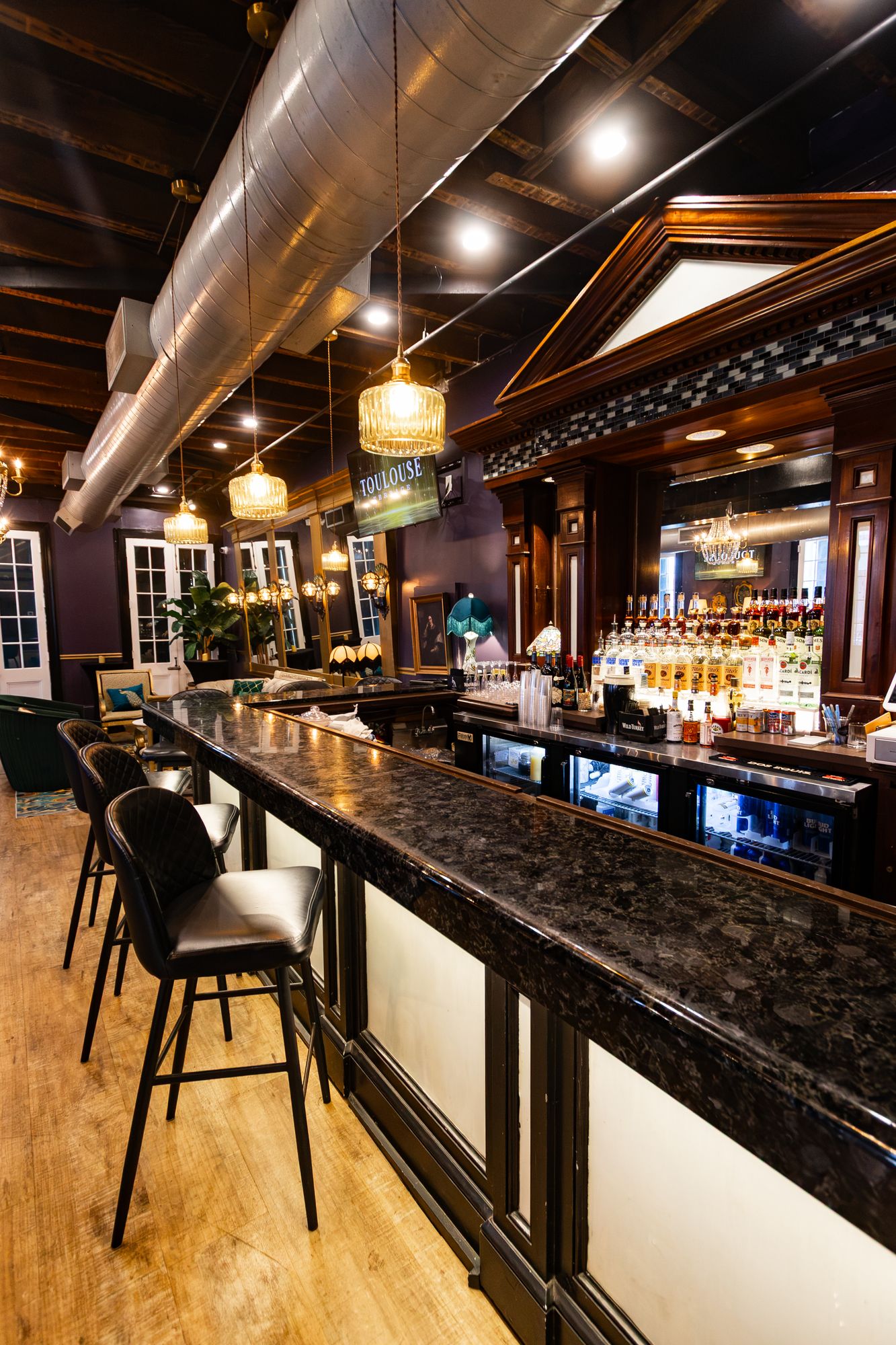 Granite-top bar with leather stools and a lit back bar