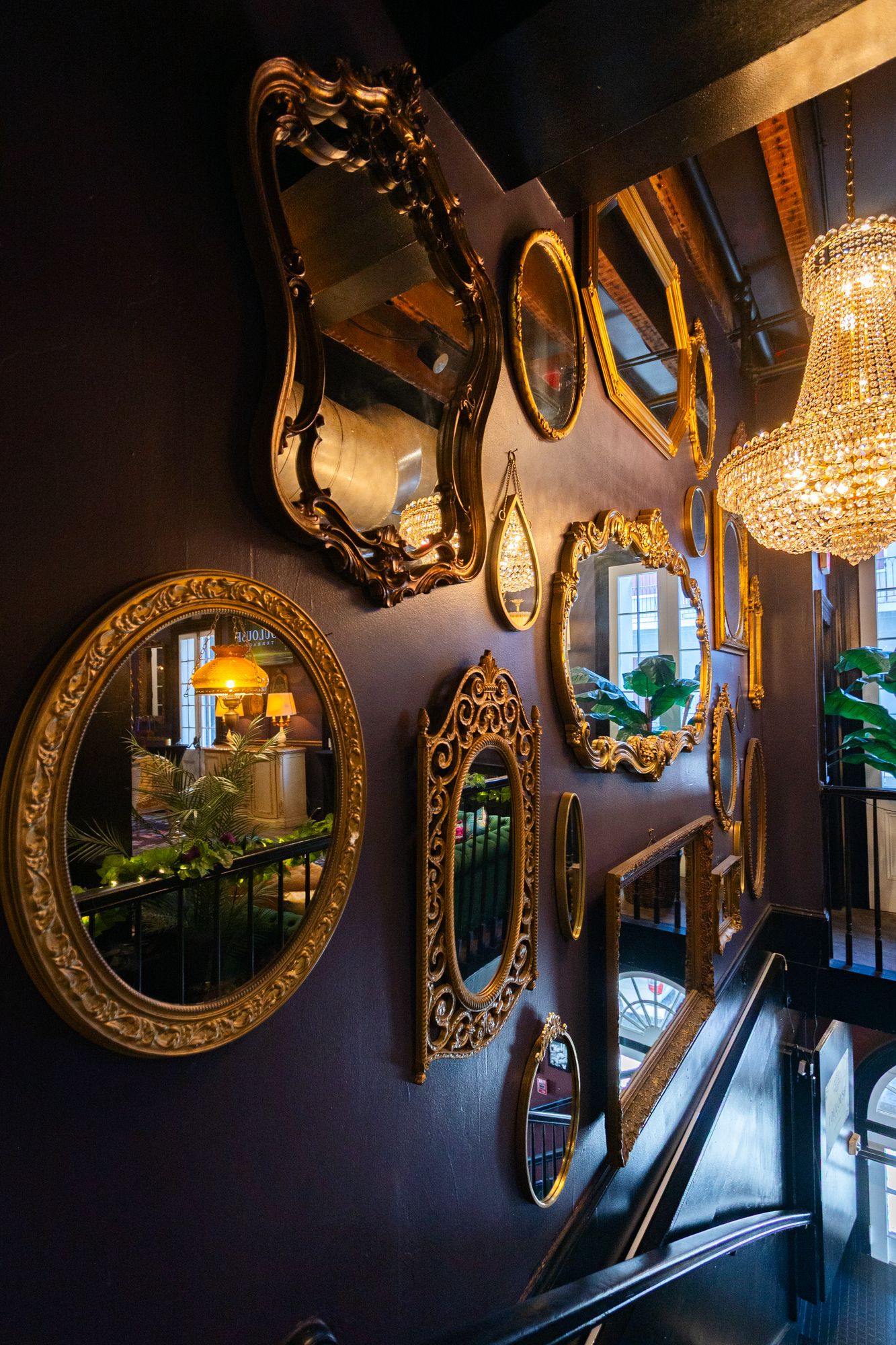 Gallery wall of ornate gold mirrors beside the stairs