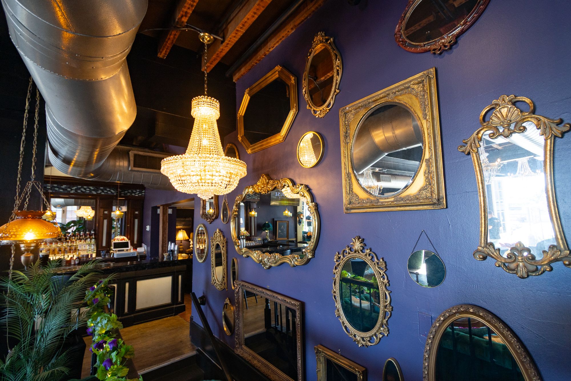 Wall of gilded vintage mirrors beside a crystal chandelier