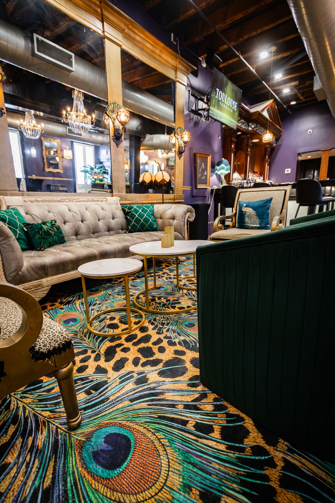 Peacock-print carpet beneath a tufted sofa and marble tables