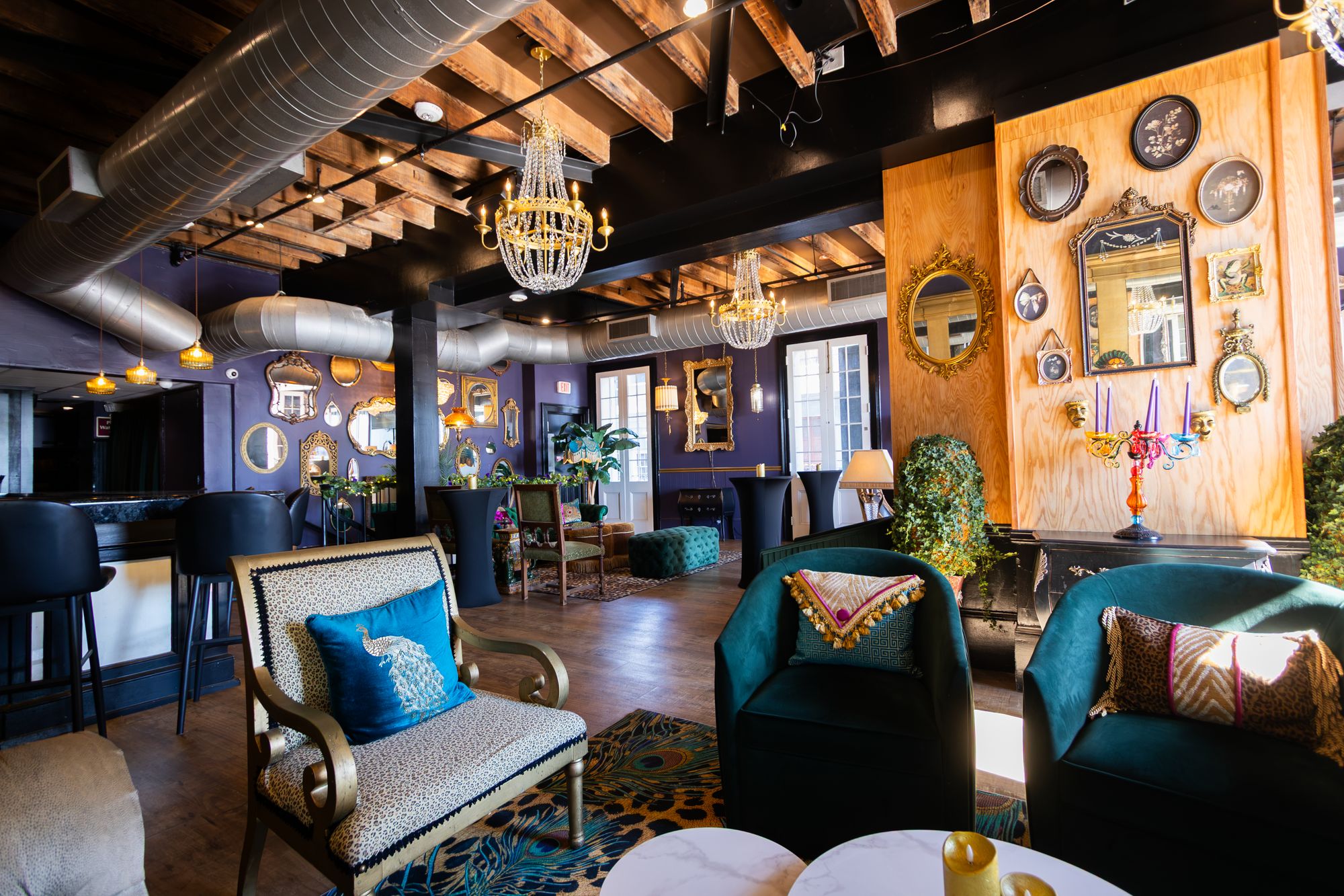 Peacock armchair and velvet club chairs facing a mirrored wood-panel wall