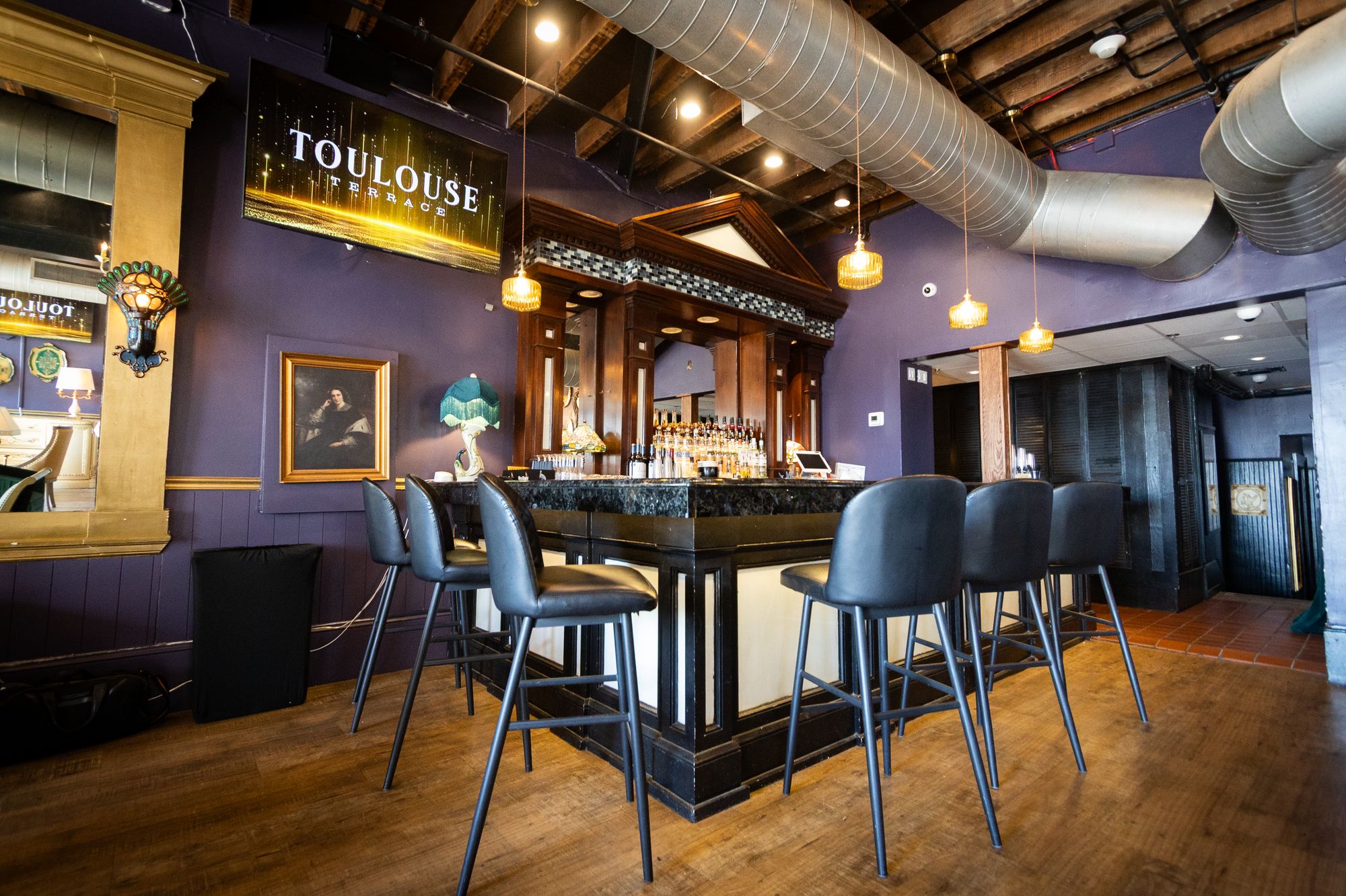 Private bar with leather stools, purple walls and the Toulouse Terrace sign
