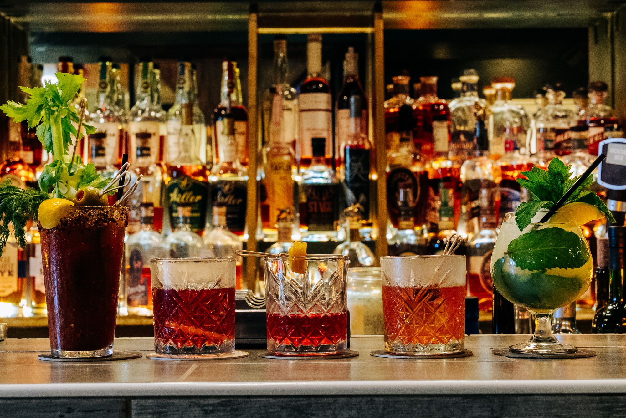 Signature cocktails lined up in front of a glowing back bar