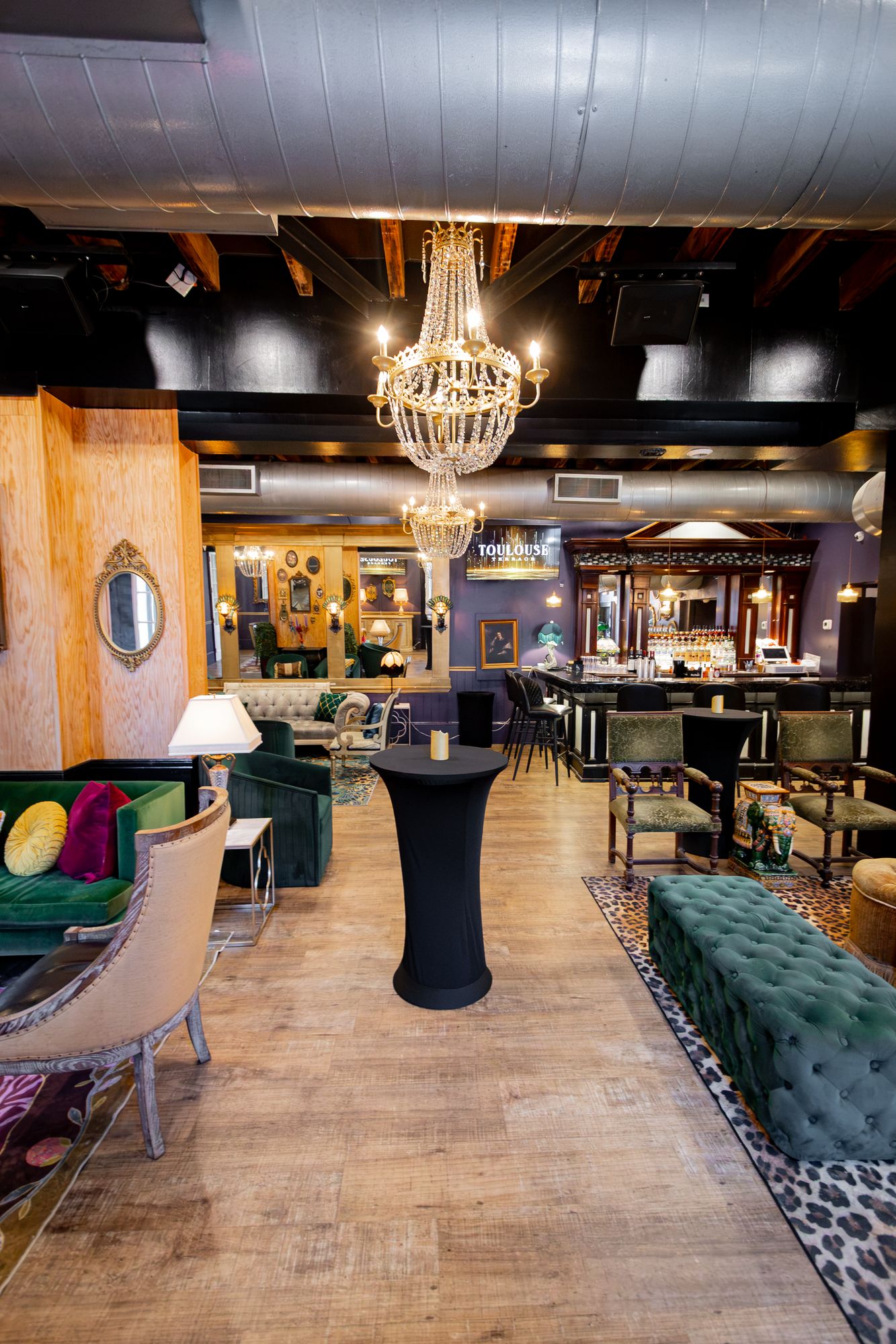 Velvet sofa, highboy tables and tufted benches leading to the bar