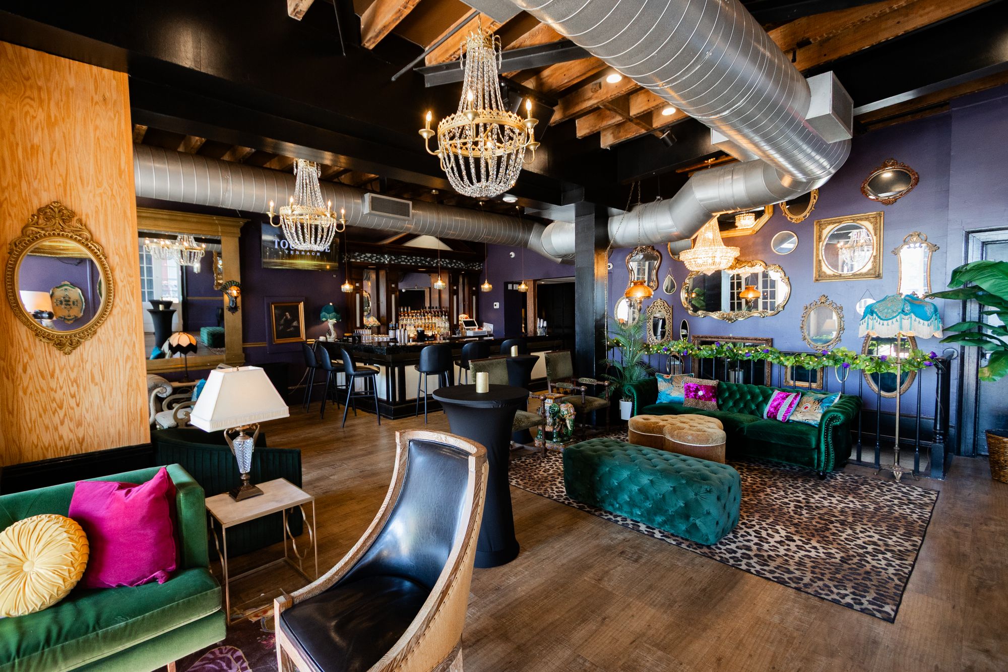 Green velvet sofa with pink pillows and a leather chair beside a chandelier