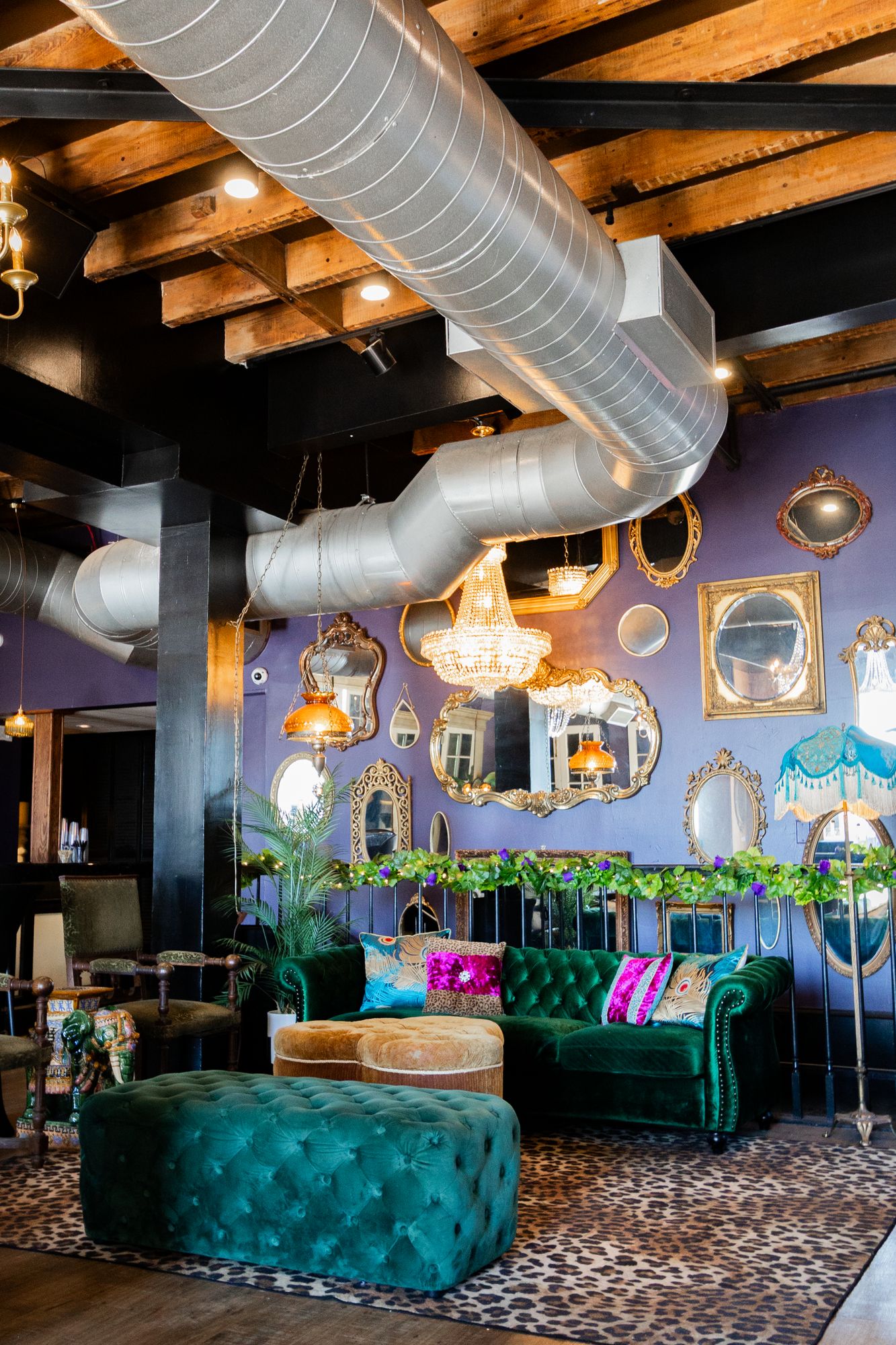 Green velvet sofa and teal tufted bench under a wall of mirrors